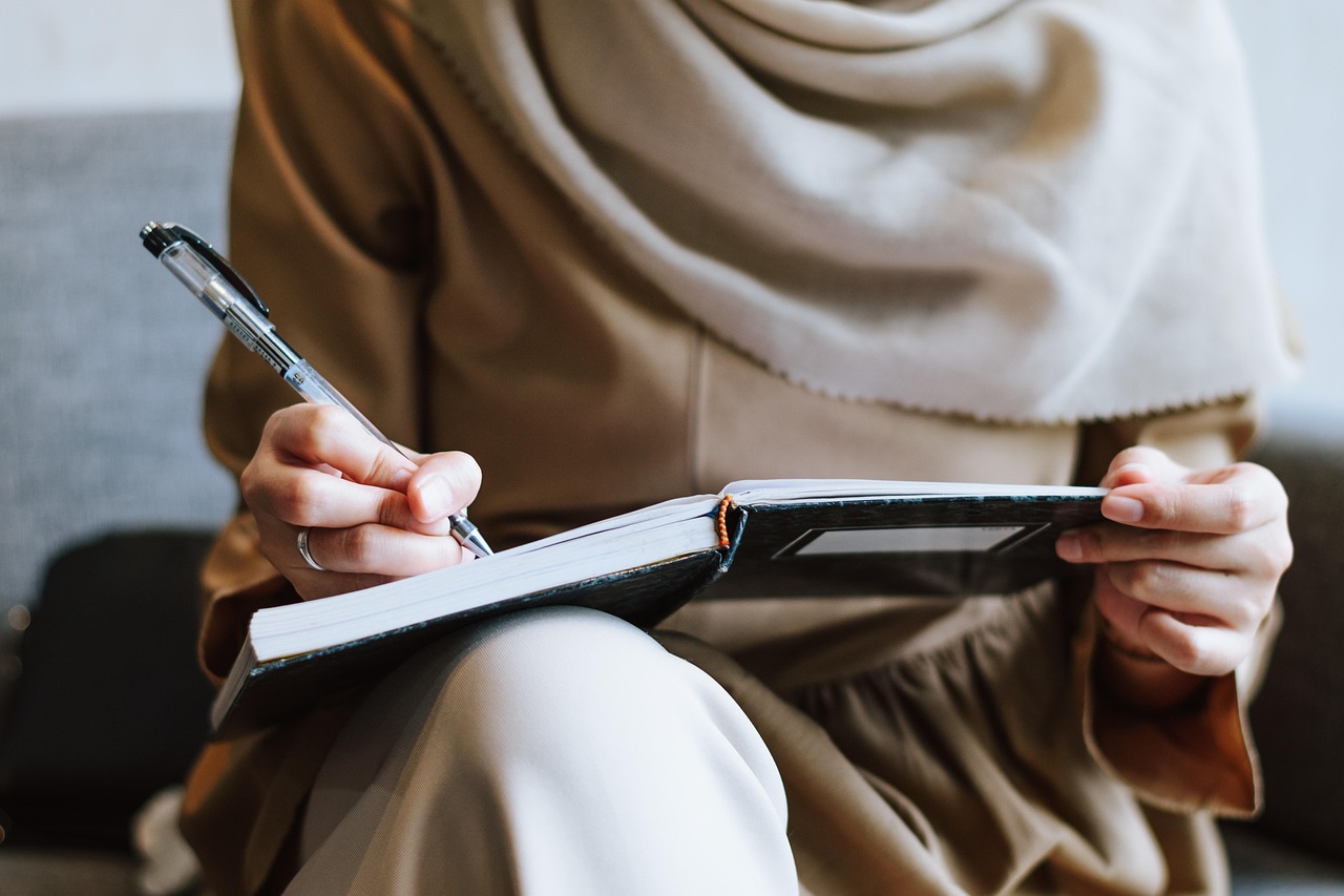 Muslim, woman, writing — Find Community Highlights and Regional Developments at eladelantado.com